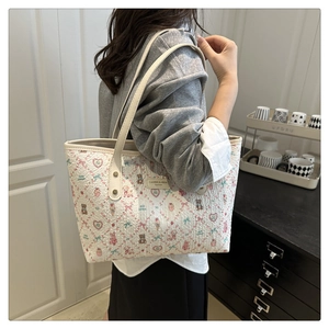 Detail of a white tote bag featuring cartoon bear prints and textured fabric finish