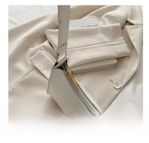Close-up of smooth gold zipper and white crocodile texture on underarm bag details