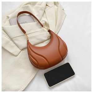 Detailed view of caramel leather crescent bag with quilted wave texture and gold buckle