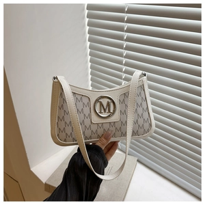 Close-up of vintage underarm bag with M letter prints and round metal logo detail