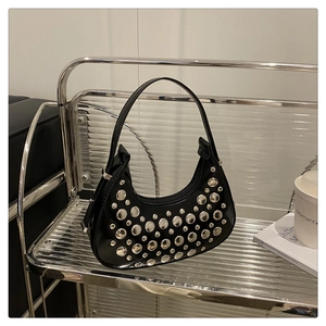 Detail shot of silver rivets and glossy black leather on a crescent shoulder bag