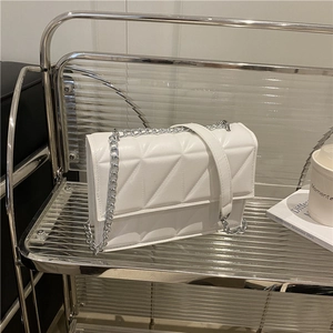 Sac bandoulière blanc matelassé avec chaîne argentée sur support minimaliste