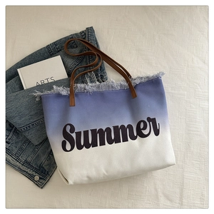 Detail of blue gradient canvas beach tote bag with fringe edge and leather handles