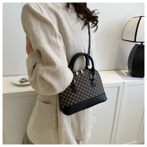 Detail of trendy shell-shaped handbag featuring brown geometric patterns and black leather strap
