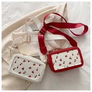 Detail view of the cherry print crossbody bags with wide straps and gold zippers
