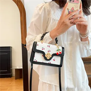 Detail of cherry print handbag featuring gold floral clasp and woven handle accessory