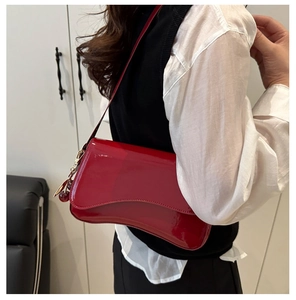 Close-up of red patent leather shoulder bag with a realistic cherry charm accessory