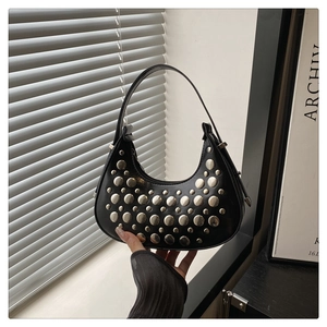 Close-up of black crescent bag featuring silver punk rivets and matte leather texture