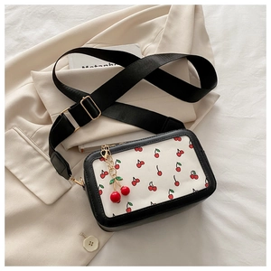 Detail of crossbody bag with cherry print and decorative metal cherry charm on the zipper