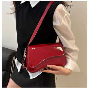 Close-up of red patent leather underarm bag with a decorative cherry metal pendant charm