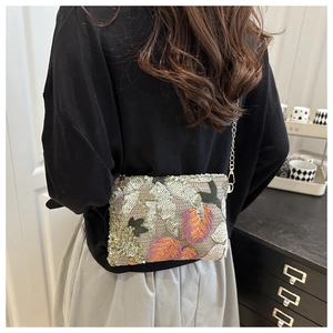 Detailed embroidery on woven clutch with colorful leaf sequins and gold chain strap