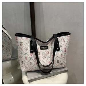 Detail of the white tote bag showing cartoon teddy bear prints and the brand logo tag
