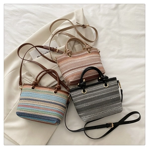 Détails de sacs seaux en paille tressée en trois coloris avec bandoulières et boucles dorées