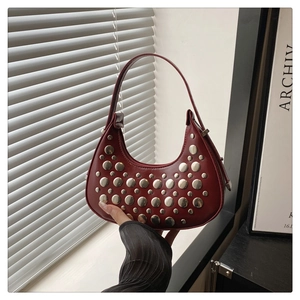 Detailed view of dark red crescent bag with silver rivets and glossy leather texture