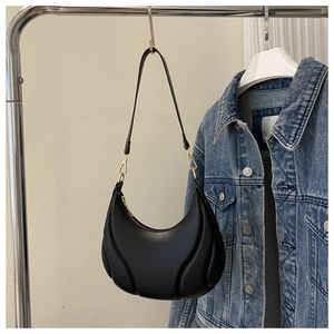 Detail of black crescent shoulder bag with quilted sections and gold metal buckle