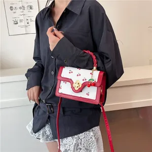 Detail of cherry print handbag showing gold flower clasp and red twisted handle