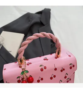 Detail of pink cherry handbag featuring spiral handles and golden metallic hardware
