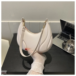 Detail of white pleated hobo bag with gold hardware and elegant textured surface