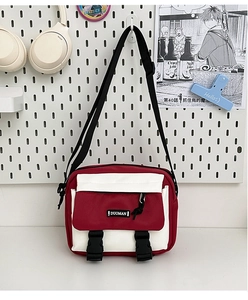 Detail of red and white canvas messenger bag featuring buckle closure and adjustable strap