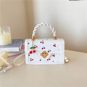 Detail of white cherry print handbag with floral gold lock and woven handle