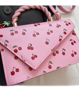 Close-up of pink cherry print bag with twisted handle and decorative charm detail