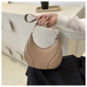 Close-up of beige moon bag showing unique curved embossed patterns and gold hardware