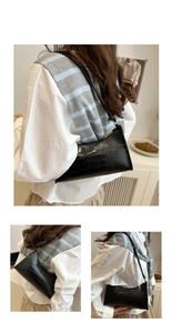 Close-up of black crocodile pattern leather underarm bag with elegant golden zipper detail