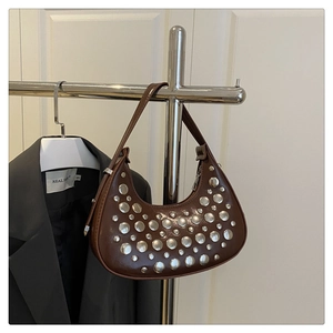 Detail of silver rivets on a brown leather crescent shoulder bag with metallic textures