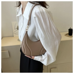 Detail view of khaki crescent shoulder bag with quilted texture and gold metal accents