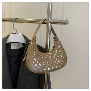 Detail view of khaki crescent hobo bag featuring silver rivets on a metallic hanger