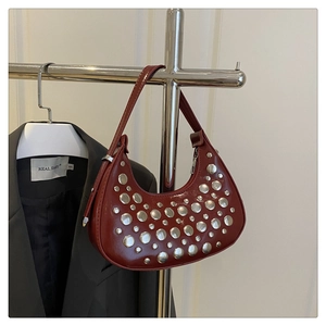 Detail of burgundy crescent bag featuring silver studs and shiny leather material