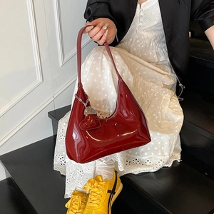 Dark red patent leather hobo bag with heart charm and silver hardware shown by a model