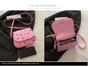 Macro detail of pink cherry print saddle bag showing internal storage for phone and makeup