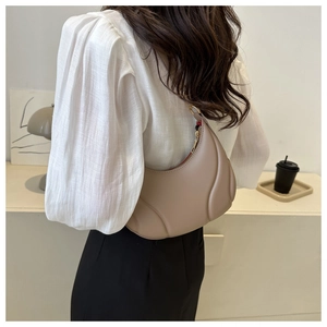 Detail of beige half-moon shoulder bag featuring stylish 3D padded streamlined patterns