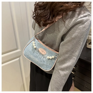 Detail of blue denim shoulder bag with pink trim and decorative pearl metal chain strap