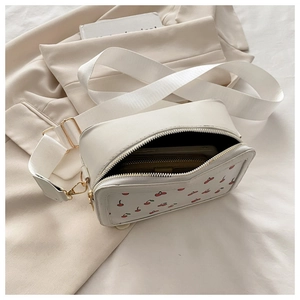 Detail view of white cherry print crossbody bag showing interior capacity and wide strap