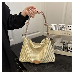 Dettaglio di borsa in paglia intrecciata a mano con trama beige e manico annodato