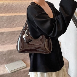 Deep brown patent leather baguette bag with silver heart pendant on a shoulder strap