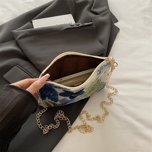 Floral embroidered envelope clutch bag with gold chain strap on black blazer