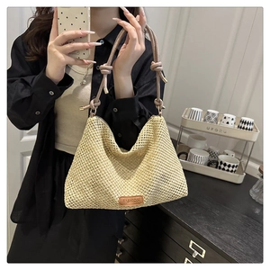 Dettaglio della borsa in paglia intrecciata con manico in pelle e etichetta moda