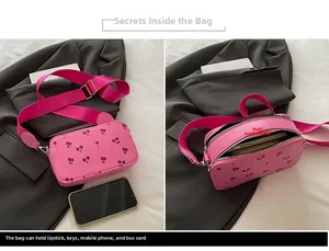 Detail view of pink crossbody bag showing dual zipper main pockets and cherry pattern