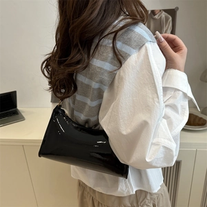 Minimalist black patent leather baguette bag for women shown as a stylish shoulder bag