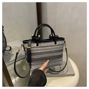 Détail du sac seau tissé avec poignée en cuir noir et boucles dorées chic