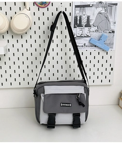 Detail view of canvas messenger bag with dual black buckle closures and adjustable strap