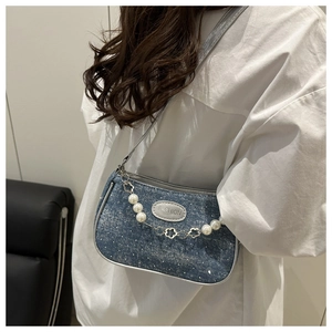 Detail of blue denim shoulder bag with pearl floral chain and fashion logo patch