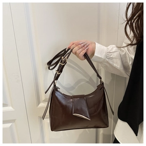 Detail of dark brown glossy PU leather hobo bag with a streamlined gold metal buckle
