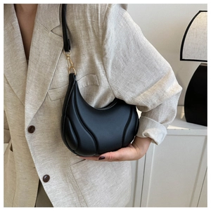 Detailed macro view of the black crescent underarm bag showing quilted ribbed leather texture