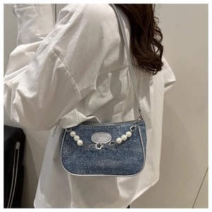 Close-up of blue denim baguette bag with white polka dots and pearl flower chain