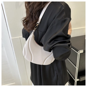 Detail view of cream crescent shoulder bag with quilted texture on black satin shirt
