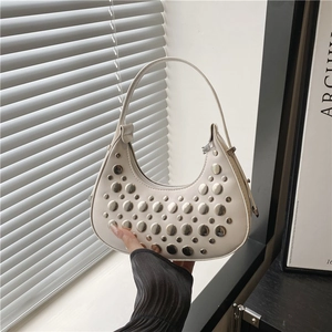White crescent underarm bag with silver studs and zipper closure in a handheld view